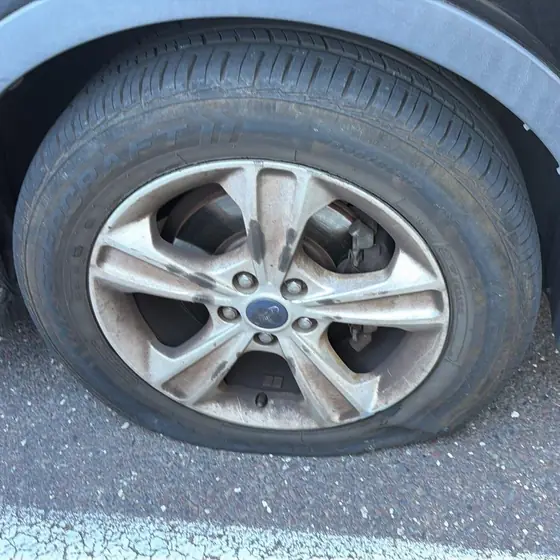 Flat tire on a gray Ford SUV in a parking lot