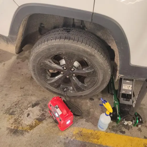 The same Jeep tire back up to pressure, with an air compressor and floor jack beside it